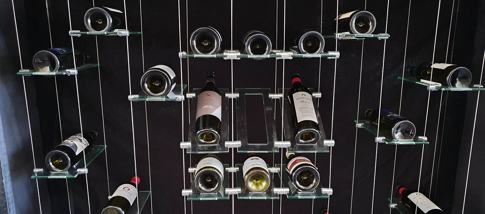 Floating glass wine rack system display with wine bottles filled Floating glass wine rack system display with wine bottles filled